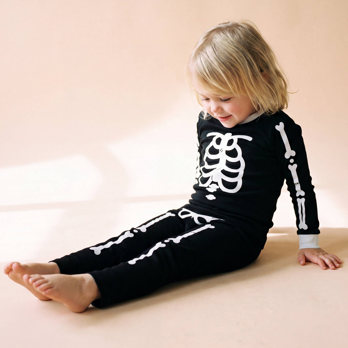 Glow in the dark skeleton pajama set, black with white bones, worn by toddler