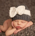 Baby wearing a grey knit beanie hat with a white knit bow