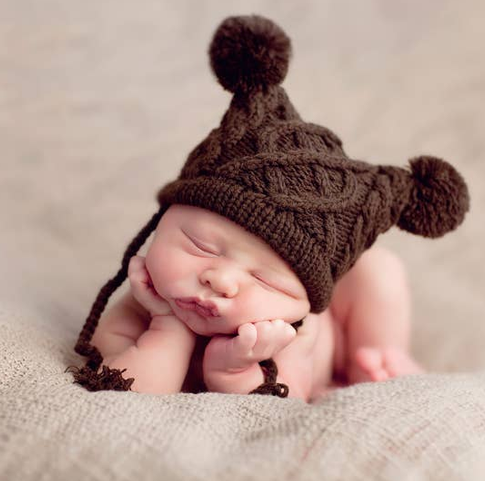 Baby knit pom pom hat, dark brown, worn by sleeping baby