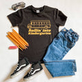 Rollin into Kindergarten black graphic tee, flat lay with school supplies