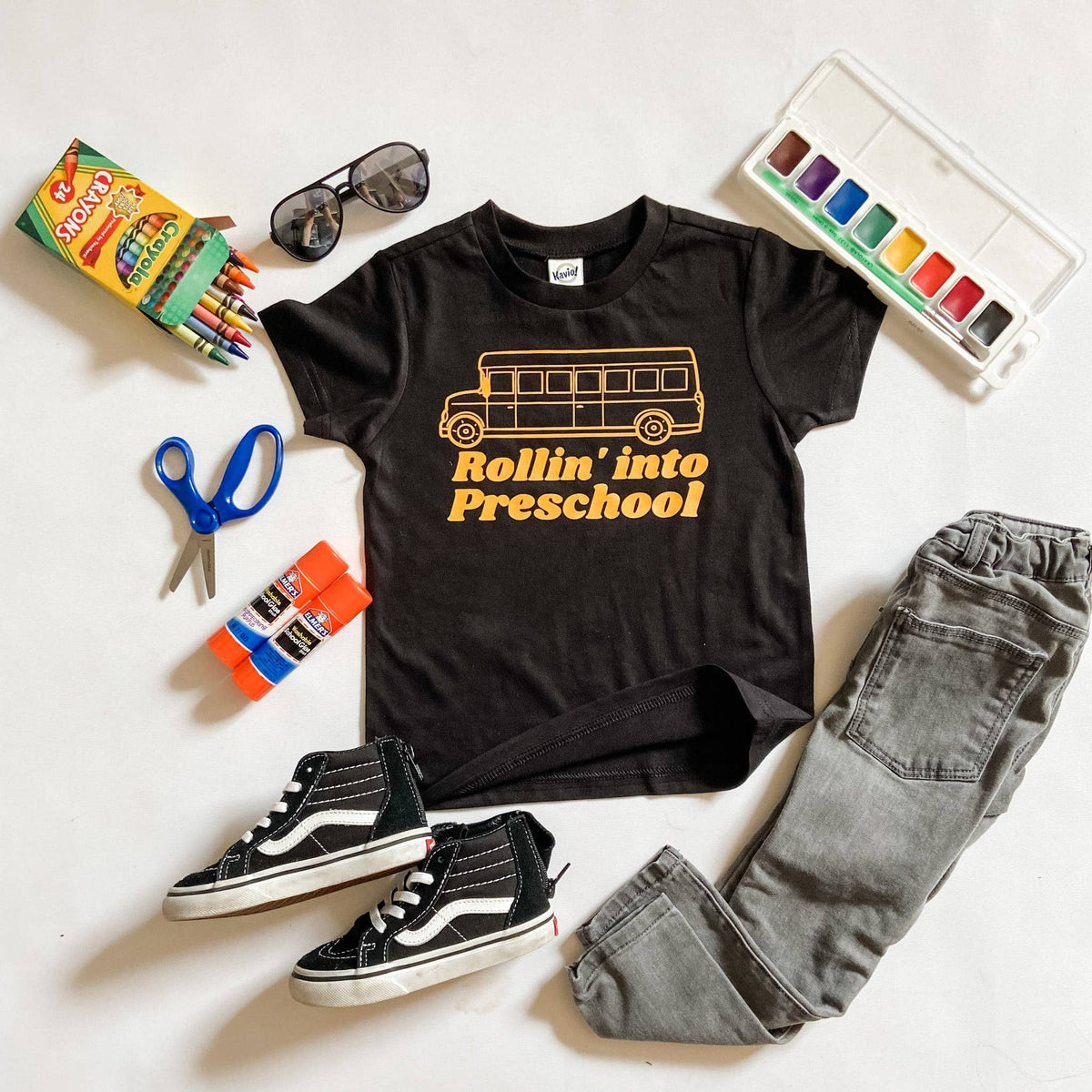 Rollin into Preschool black graphic tee, flat lay with school supplies