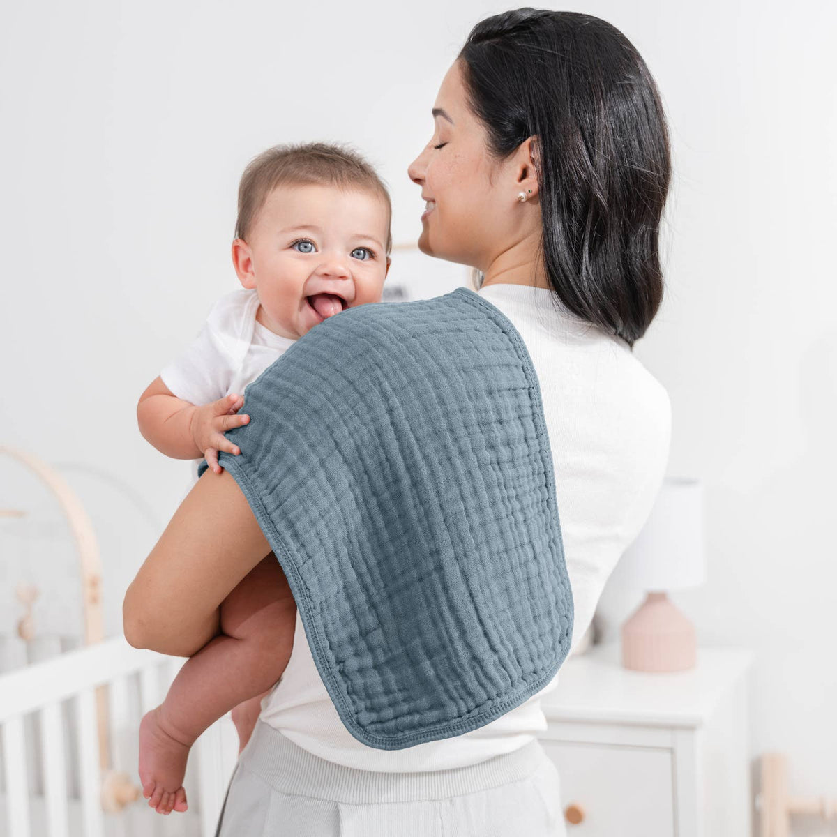 Mom with a smiling baby and a blue muslin burp cloth over her shoulder