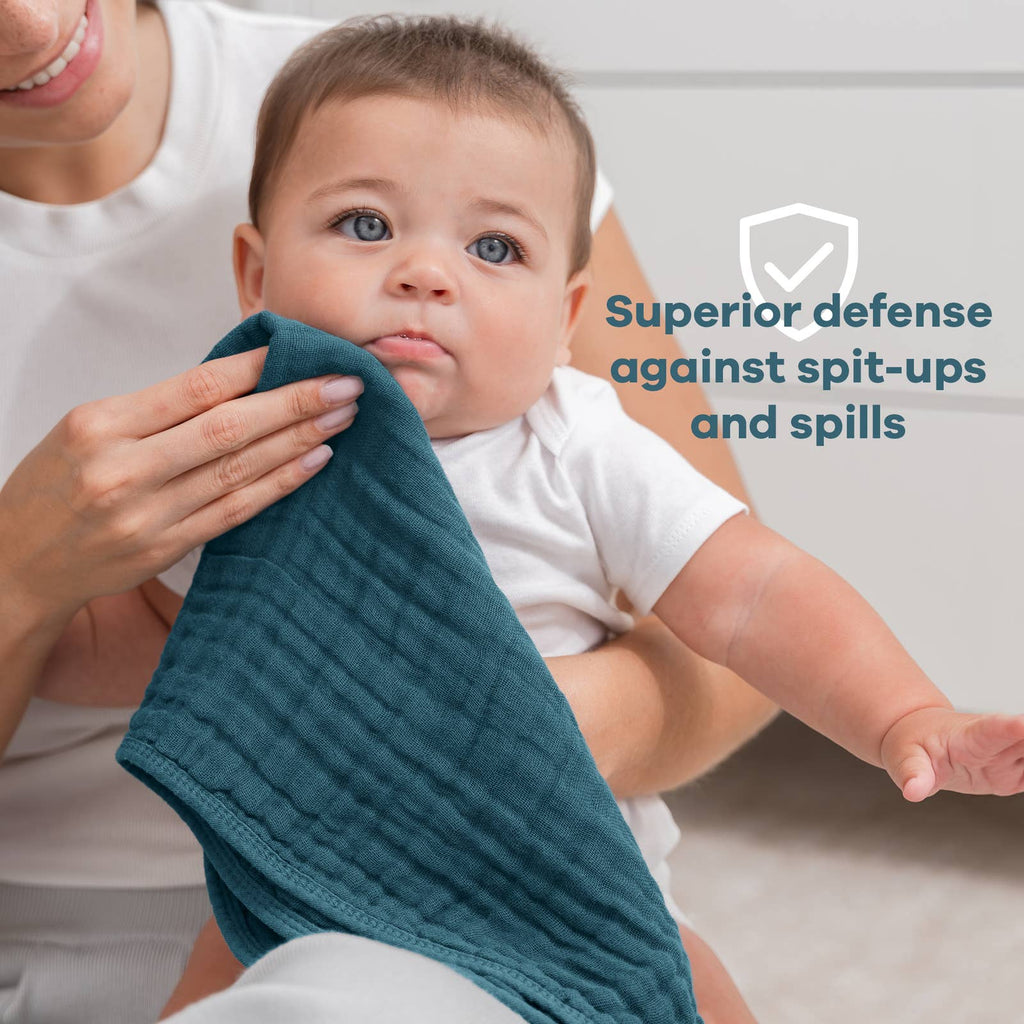 Baby holding a teal muslin burp cloth