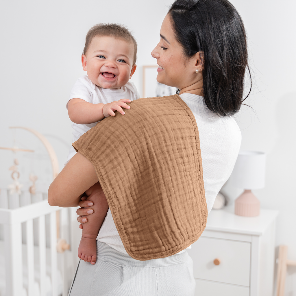 Mom with a smiling baby and a muslin burp cloth over her shoulder
