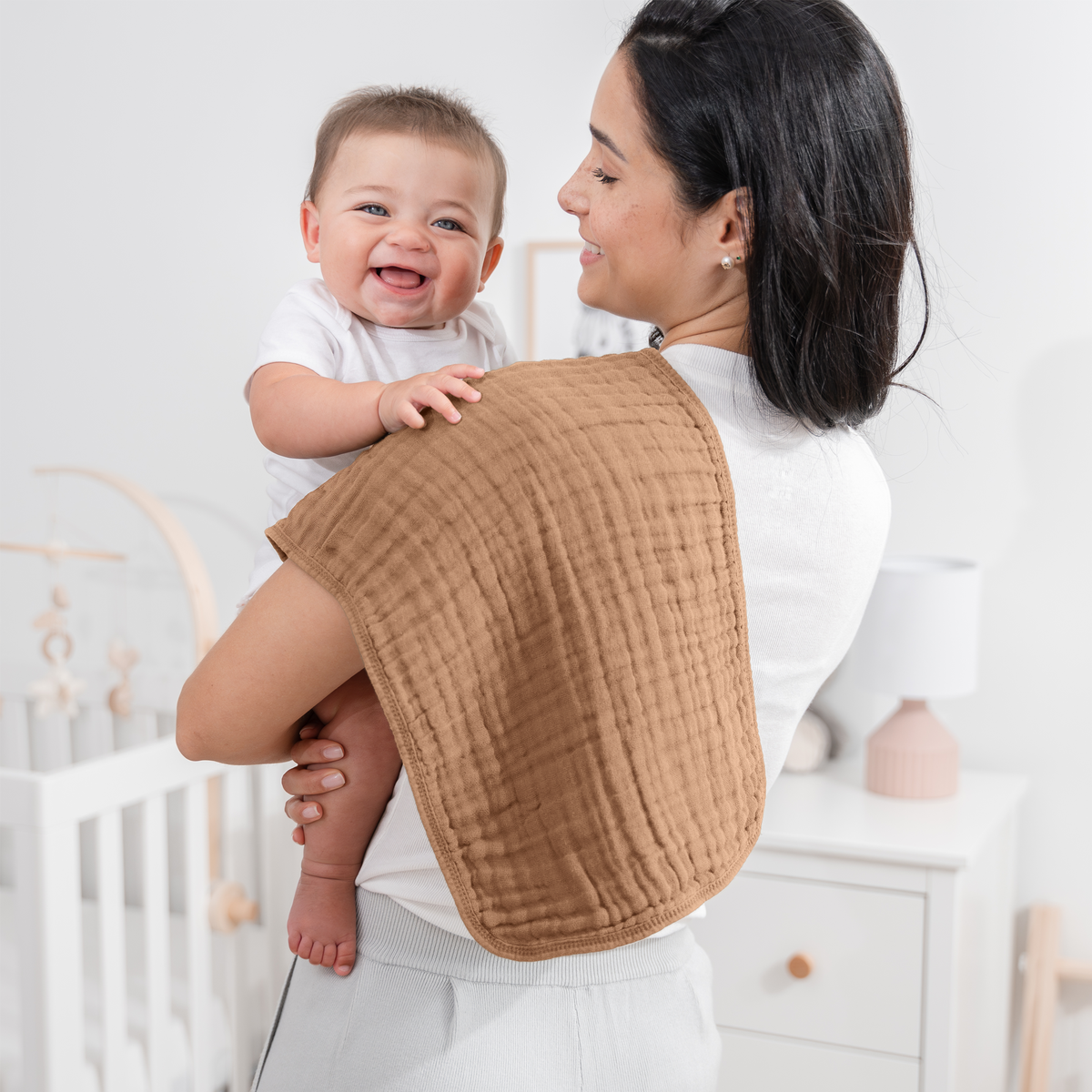 Mom with a smiling baby and a muslin burp cloth over her shoulder