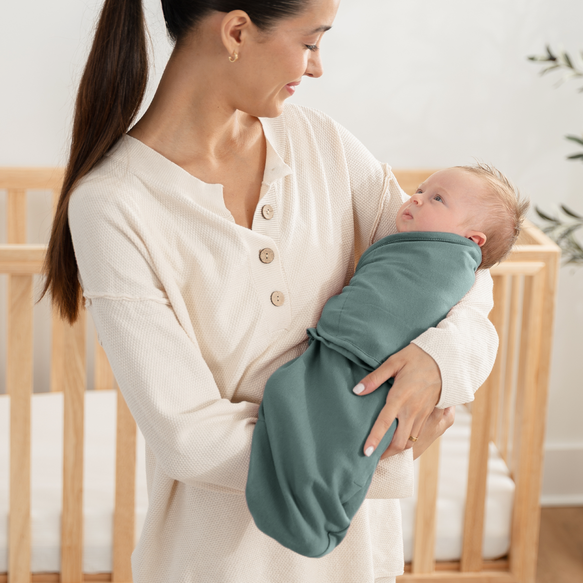 Mom holding a baby wrapped in a sage-teal easy swaddle from the blues and greys set