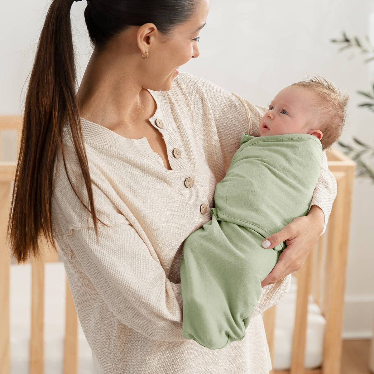 Mom holding a baby in the sage green easy swaddle