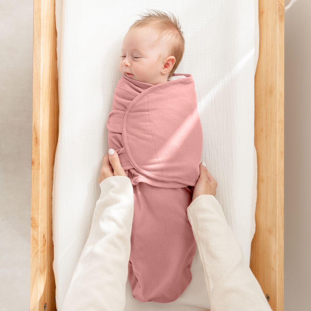 Newborn sleeping in a blush easy swaddle