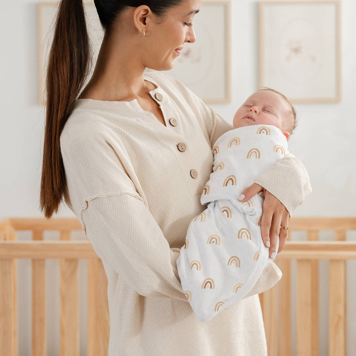 Mom holding a baby in the sand rainbow print easy swaddle