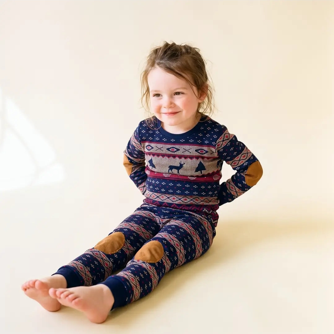 Toddler wearing the navy Fair Isle reindeer Christmas pajama set with tan elbow and knee patches