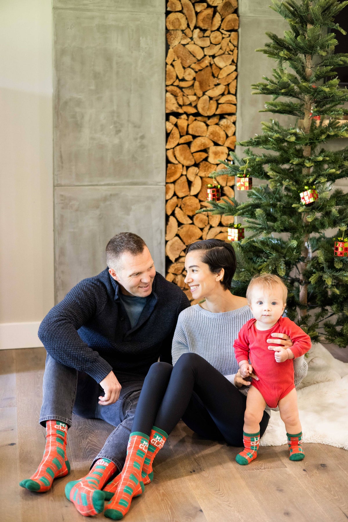 Family in matching plaid Christmas socks by the tree