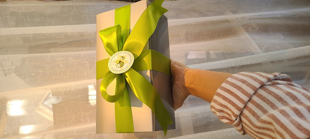 Gift box tied with a lime green satin bow and bee sticker