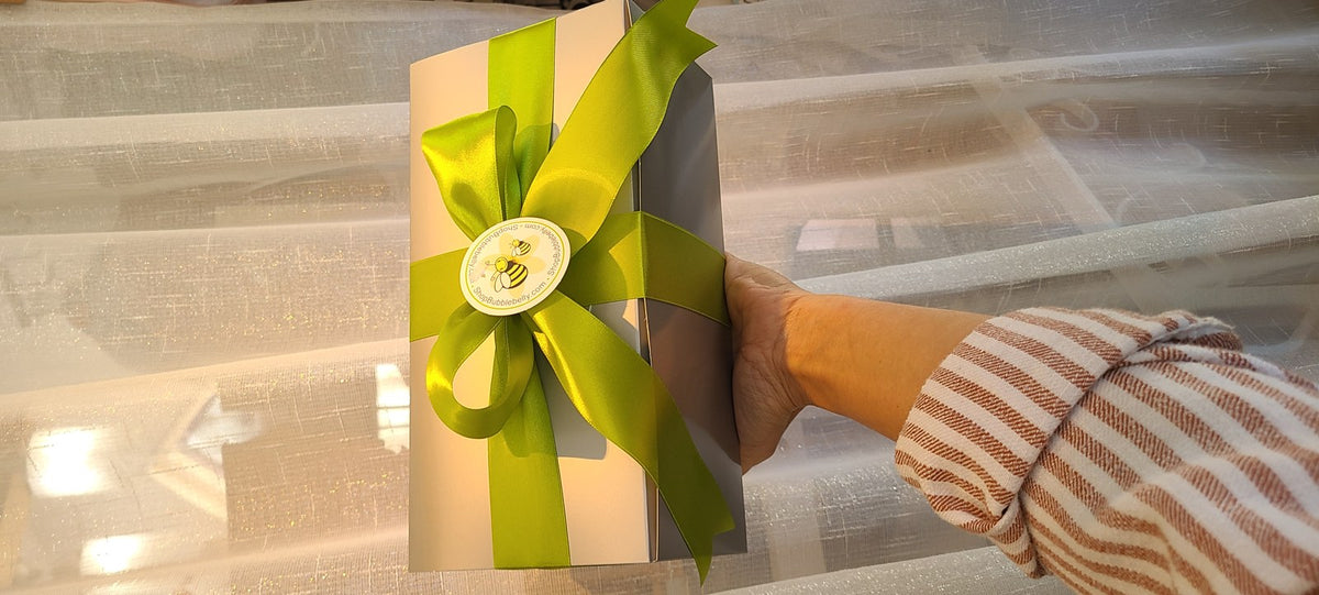 Gift box tied with a lime green satin bow and bee sticker