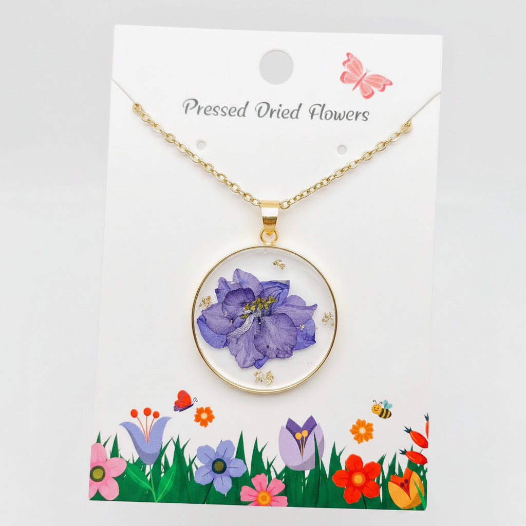 Purple pressed delphinium round pendant necklace, on its pressed dried flowers card