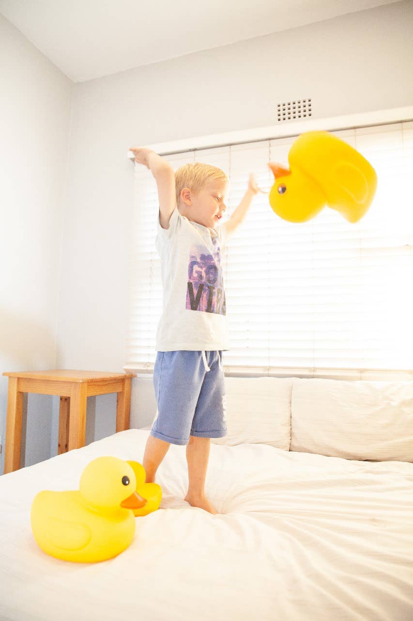 Boy playing with giant yellow rubber ducks on the floor