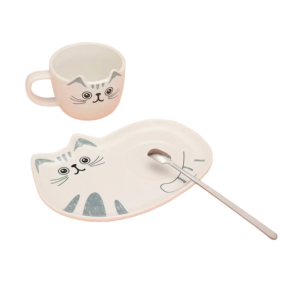 Cat-shaped mug, plate, and spoon on a pink background