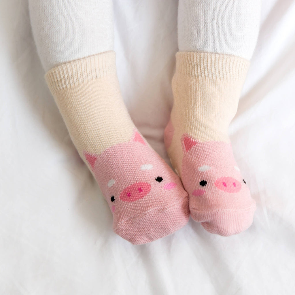 Baby wearing cream and pink pig grip ankle socks