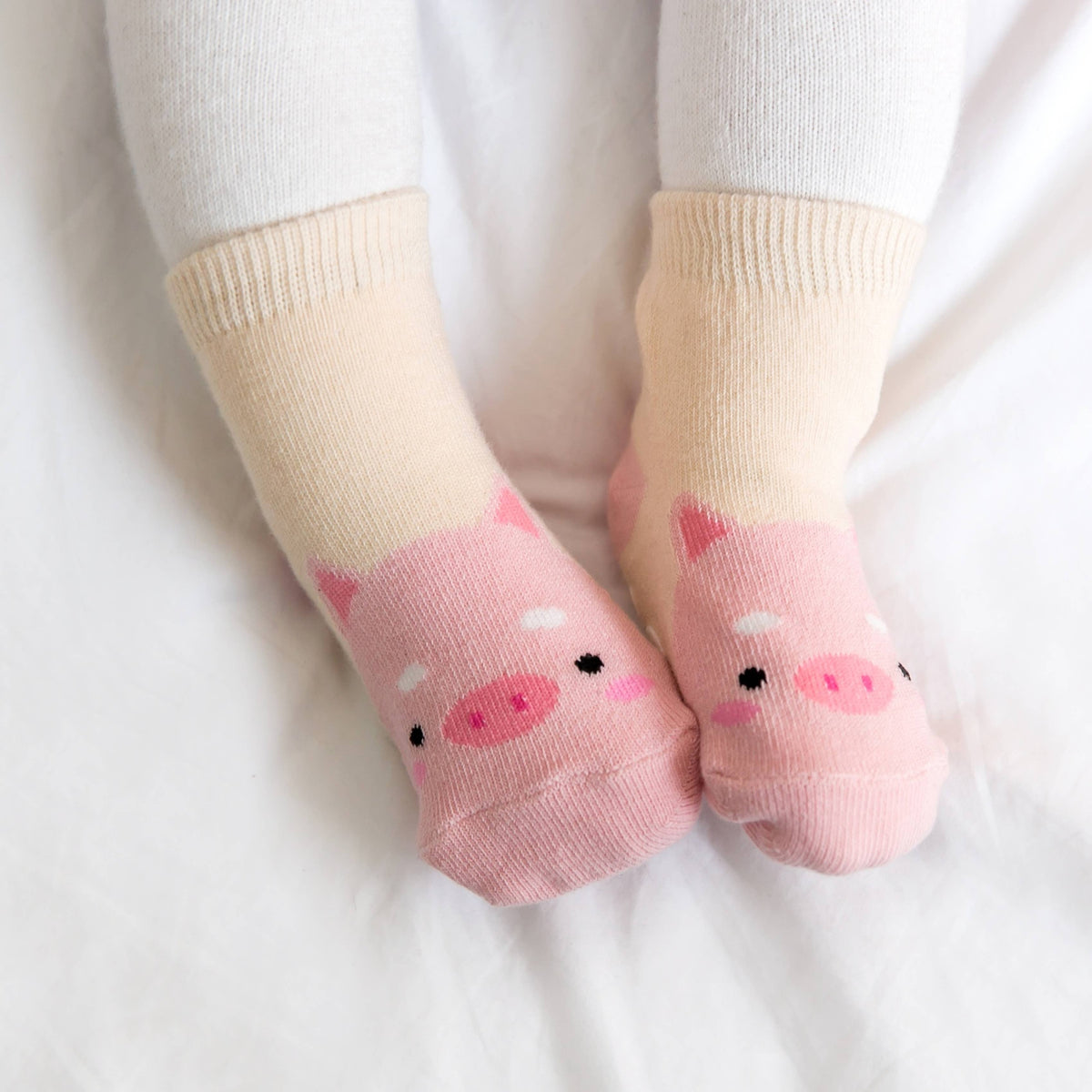 Baby wearing cream and pink pig grip ankle socks