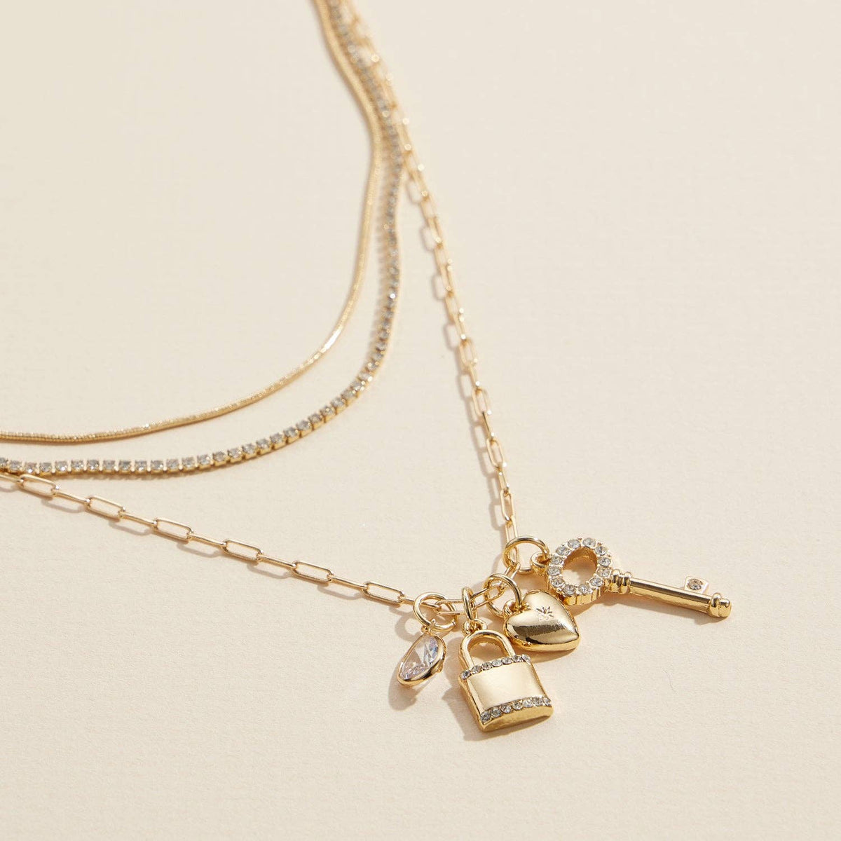 Layered gold necklace with lock, key and heart charms, charm detail