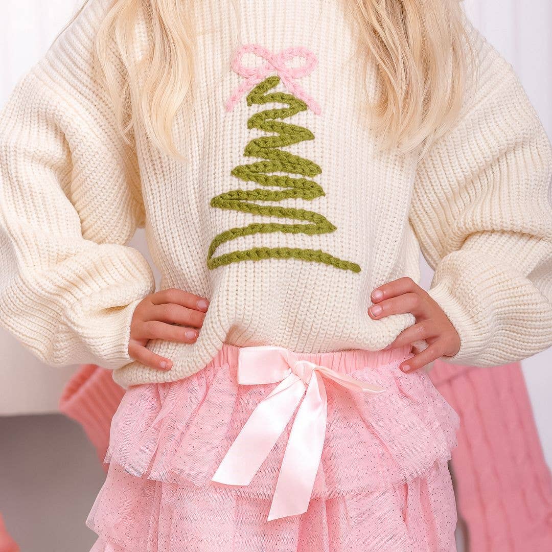 Girl wearing the Christmas tree sweater with a pink tulle skirt