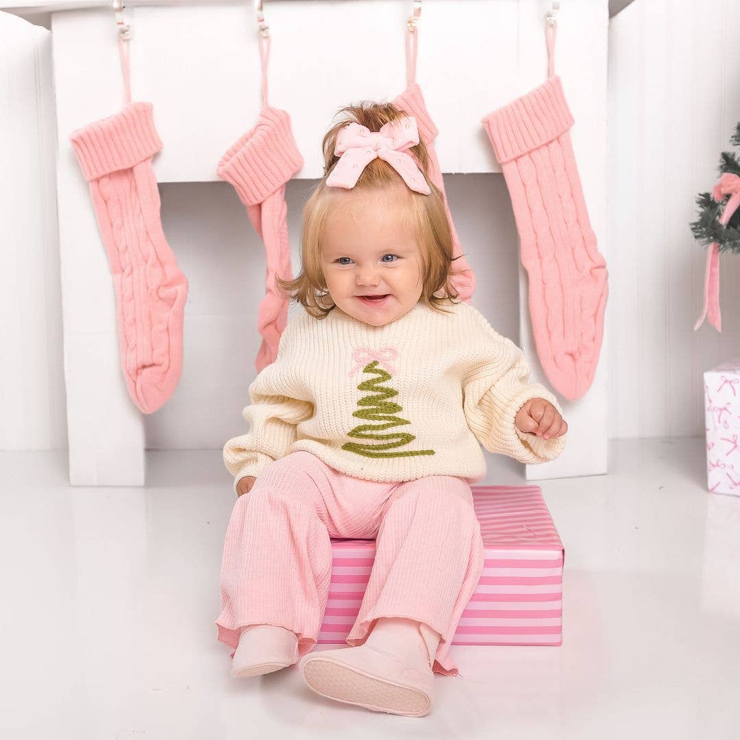 Toddler in the Christmas tree sweater by the stockings