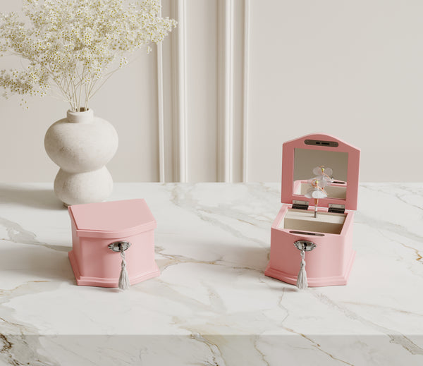 Small and medium pink ballerina music boxes on a dresser