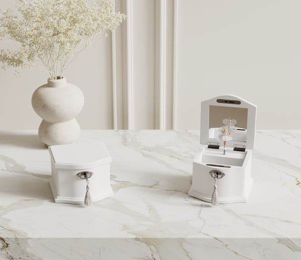 Small and medium white ballerina music boxes on a dresser