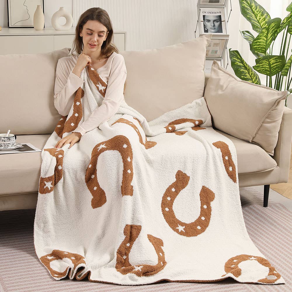 Woman wrapped in the tan horseshoe throw blanket on a sofa