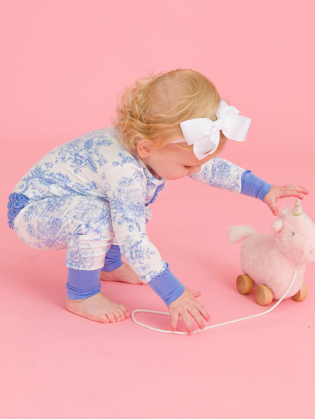 RuffleButts baby girl bamboo ruffled romper in periwinkle blue butterfly toile, toddler playing on the floor