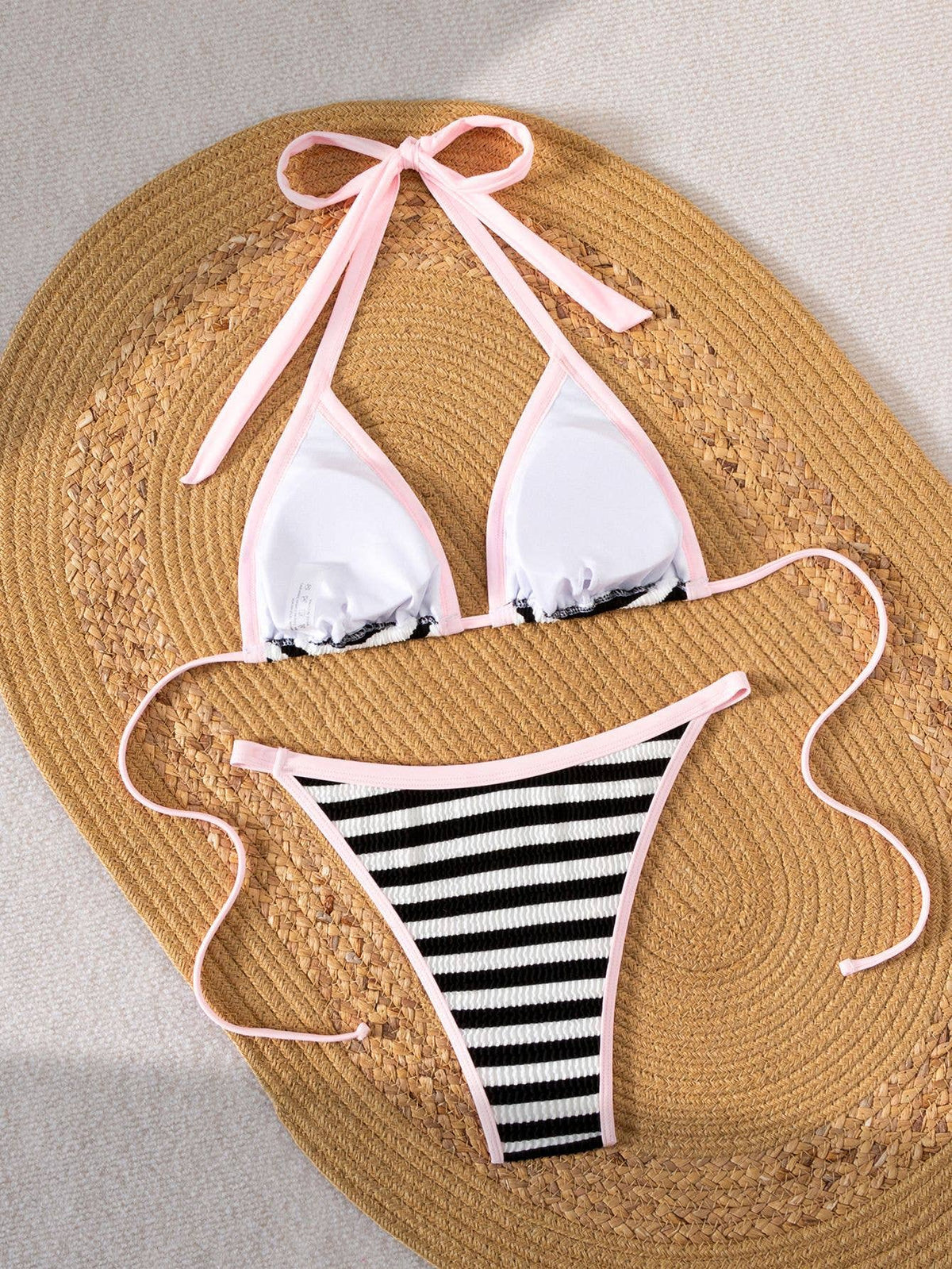 Women's and teens black and white stripe bikini with pink trim, flat lay angle