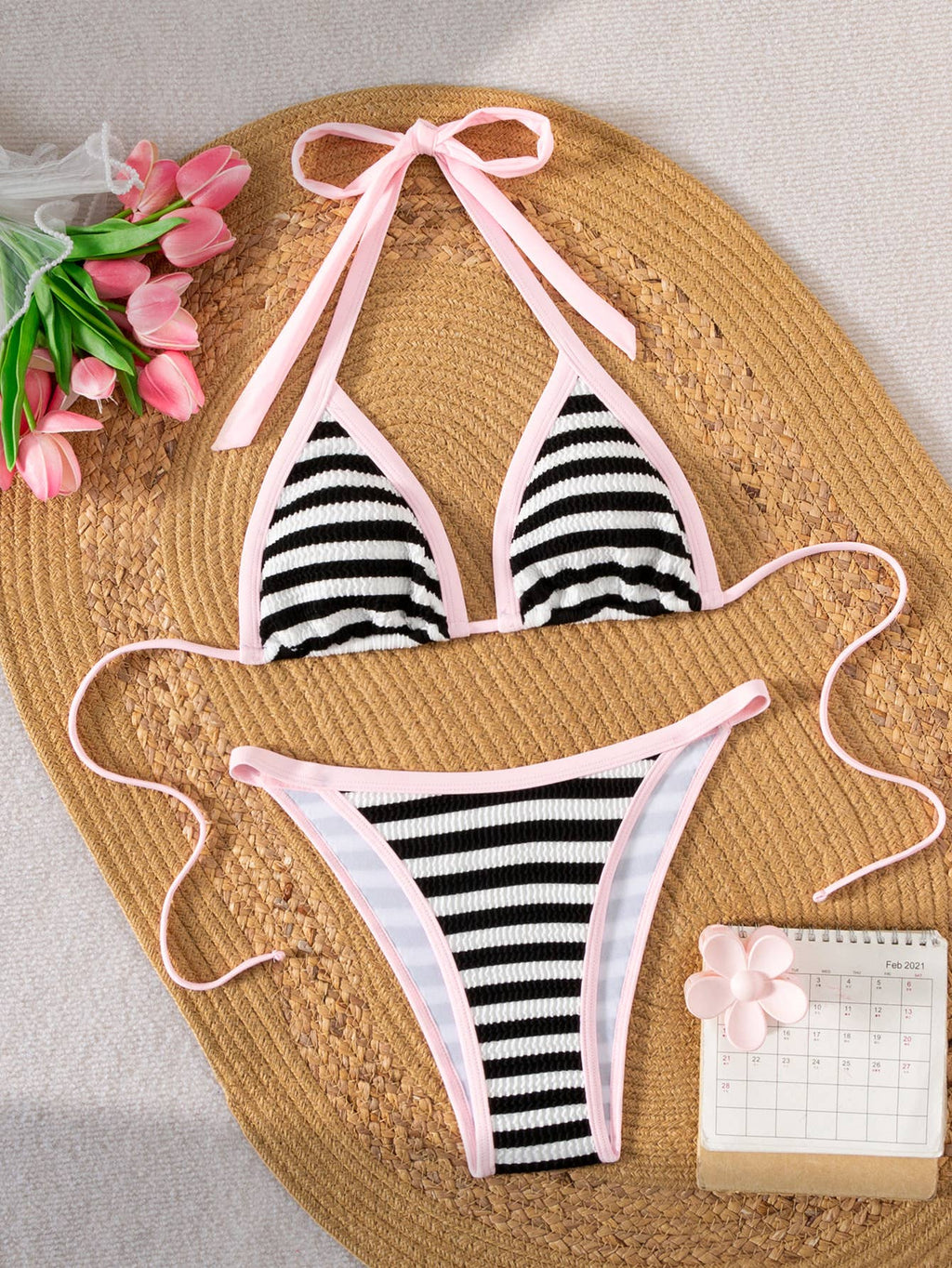 Women's and teens black and white stripe bikini with pink trim, flat lay